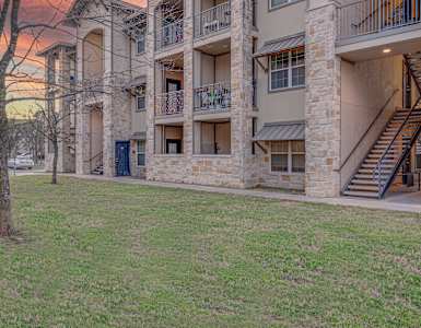 A large apartment complex with a grassy area in front. at Logan Ridge Apartments, San Marcos, 78666