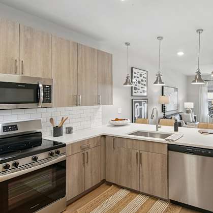 A modern kitchen with wooden cabinets and stainless steel appliances at The Hendry Apartments, Fort Myers, FL, 33905