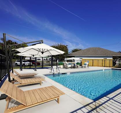 A pool with sun loungers and a white umbrella.