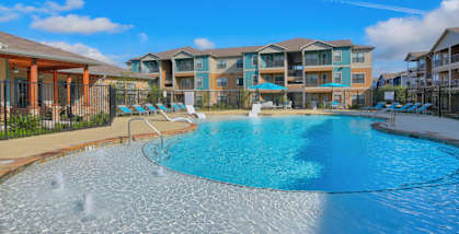 A large swimming pool in front of a resort.