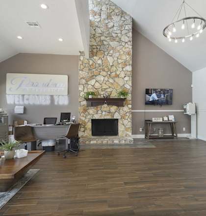 A living room with a stone fireplace and a flat screen TV mounted on the wall.