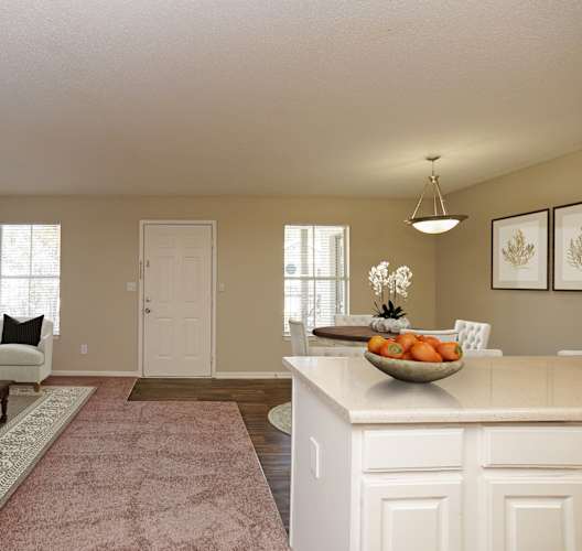 A well-lit, spacious living room with a white sofa, a coffee table, and a large kitchen island.