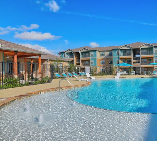 A large swimming pool in front of a resort.
