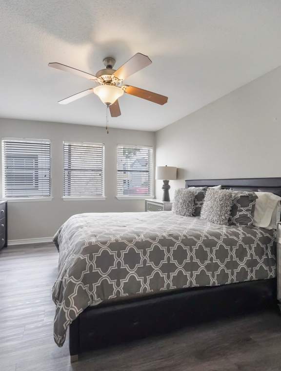 A bedroom with a bed, dresser, and ceiling fan.