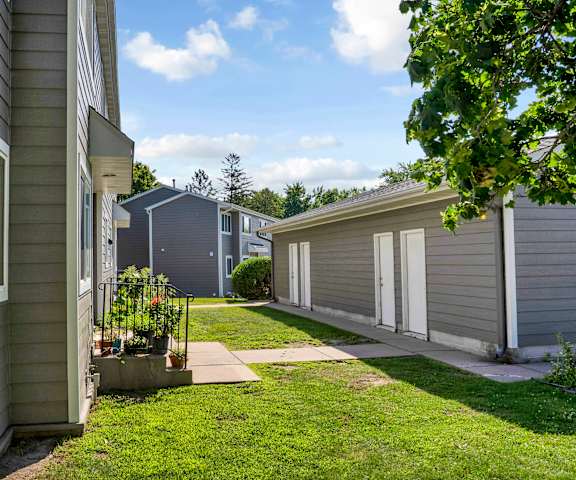 A row of houses with green lawns and trees in the background.
