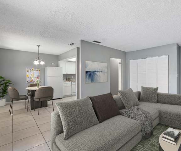 A living room with a grey couch and a dining table.