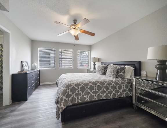 A bedroom with a bed, dresser, and ceiling fan.