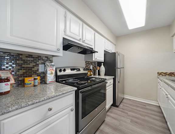 A kitchen with white cabinets and a stainless steel stove.