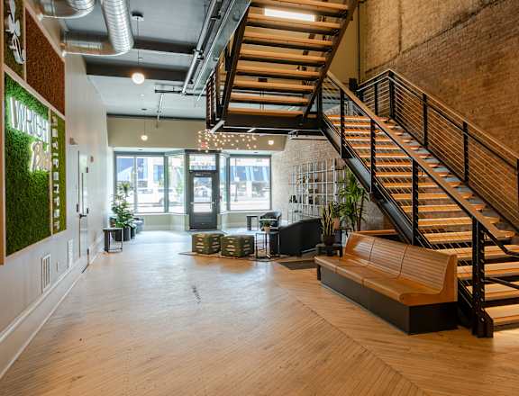A staircase with a wooden handrail and a bench at the bottom.