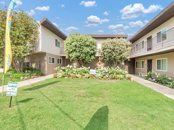 a yard in front of a building with grass and flowers