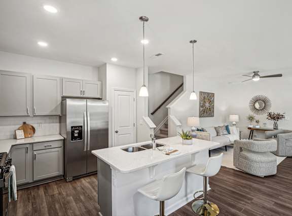 a kitchen and living room with a white counter top and a stainless steel refrigerator