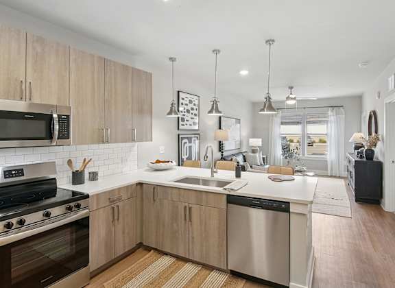 A modern kitchen with wooden cabinets and stainless steel appliances at The Hendry Apartments, Fort Myers, FL, 33905