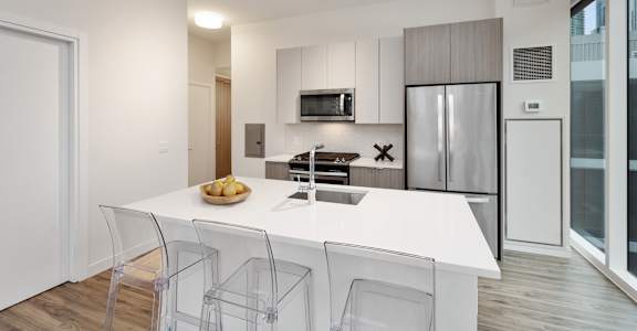 a kitchen with a white counter top and a stainless steel refrigerator