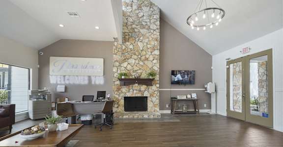 A living room with a stone fireplace and a flat screen TV mounted on the wall.