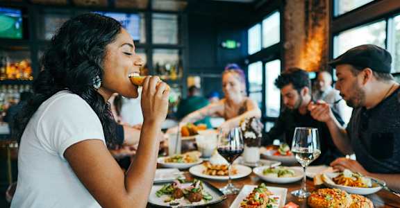 a group of people sitting at a table eating food at a restaurant