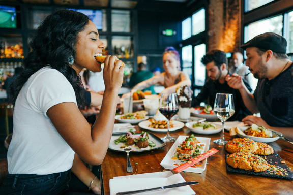 a group of people sitting at a table eating food at a restaurant