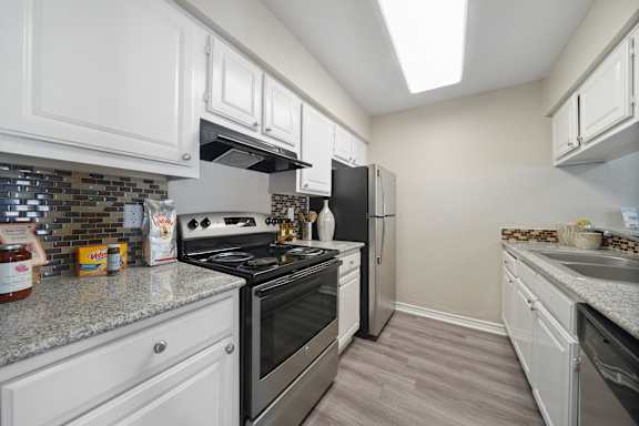 A kitchen with white cabinets and a stainless steel stove.