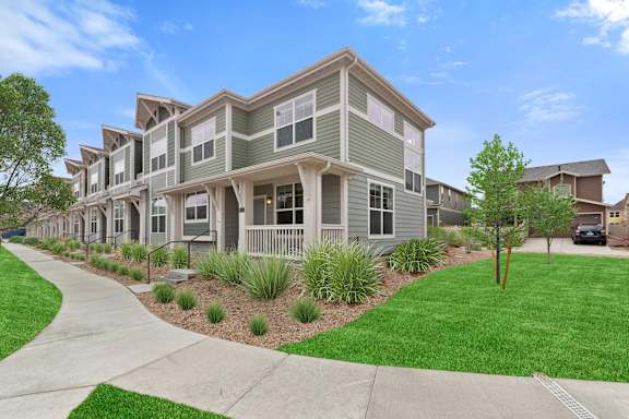 an apartment building with green grass and a sidewalk