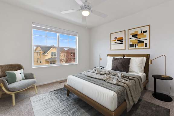 a bedroom with a large window and a ceiling fan
