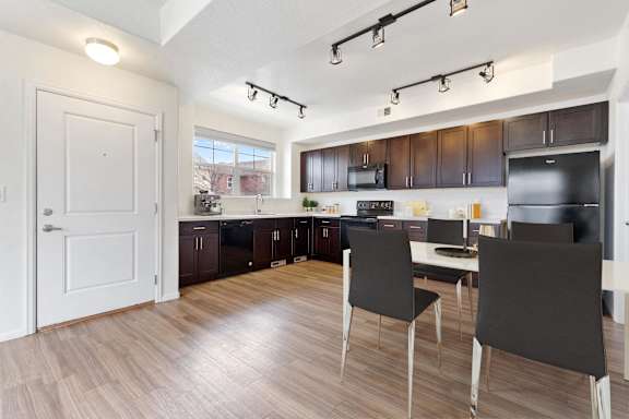 a kitchen and dining room with dark wood cabinets and a black refrigerator