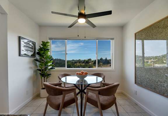 A dining room with a table and chairs and a ceiling fan.