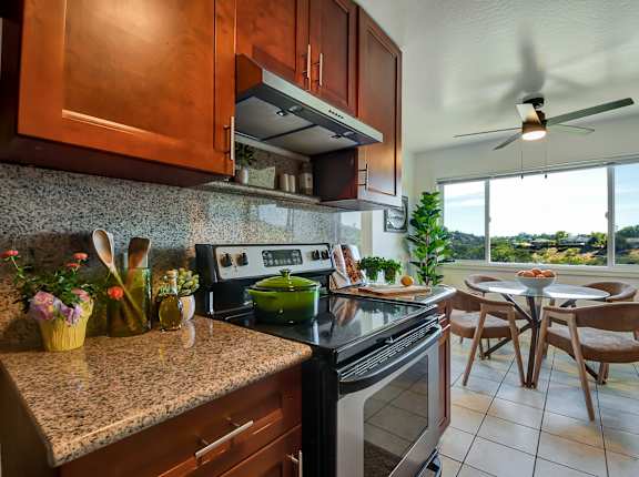 A kitchen with a stove top oven and a fan.