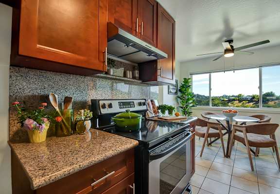 A kitchen with a stove top oven and a fan.