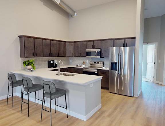A kitchen with a white counter top and a refrigerator.