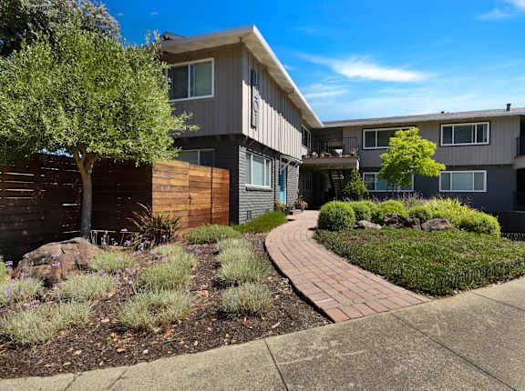 A modern apartment complex with a landscaped garden in front.