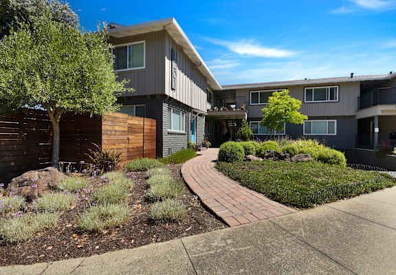 A modern apartment complex with a landscaped garden in front.