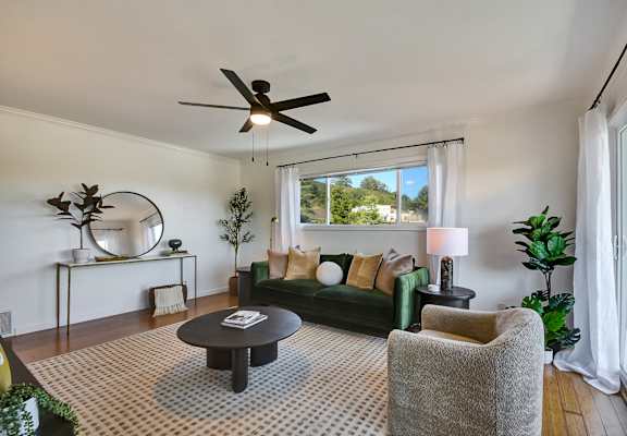 A living room with a green couch, a coffee table, and a ceiling fan.