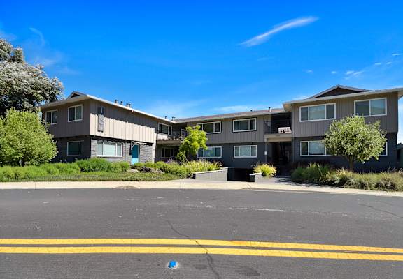 A large apartment complex with a parking lot in front.