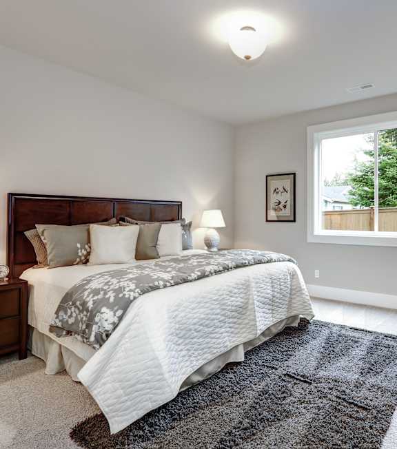 A bedroom with a large bed and a chair.