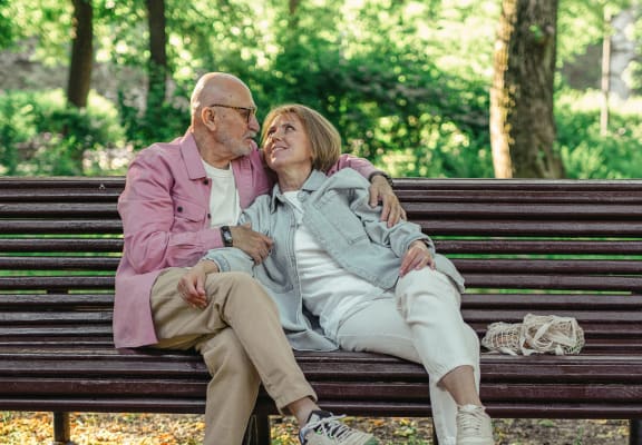 a man and woman sitting on a bench in a park