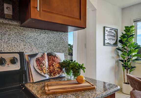 A kitchen with a black stove top oven and a cutting board with an orange on it.