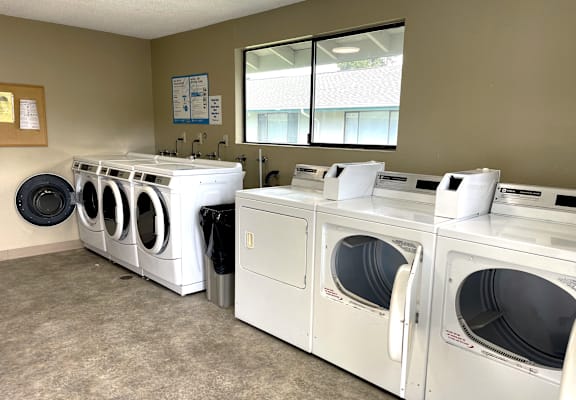 A row of white front load washing machines in a laundromat.