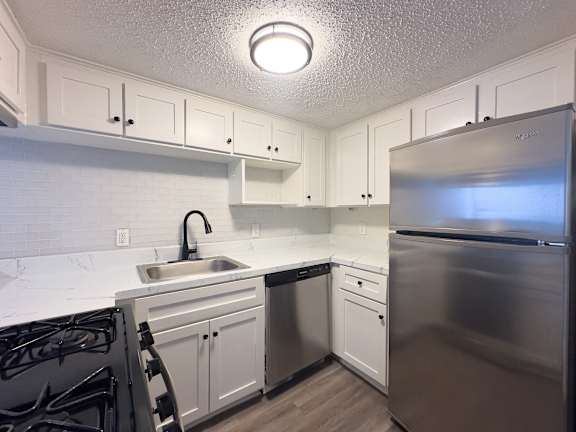 A kitchen with a stove, sink, and refrigerator.