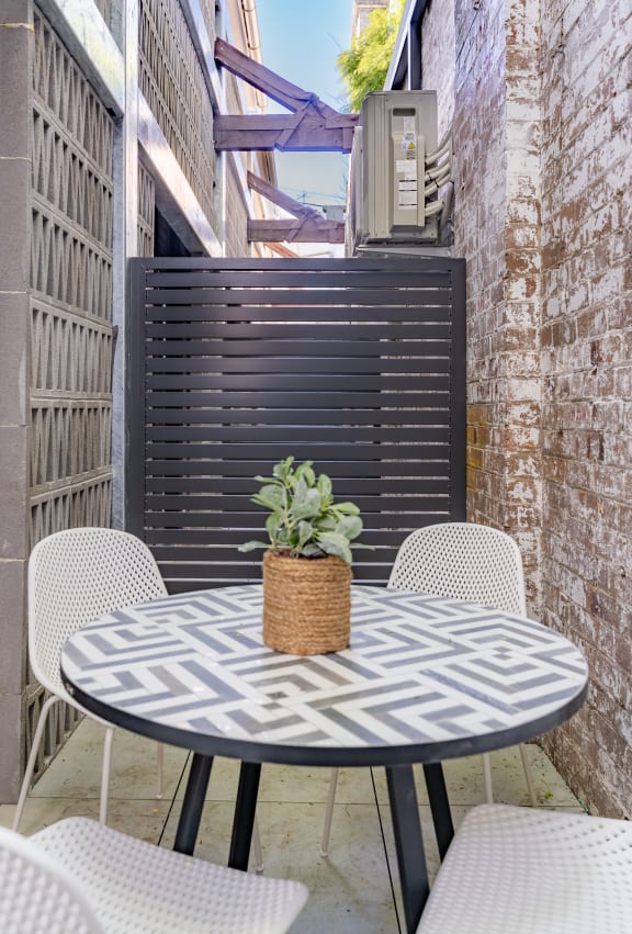 a patio with a table and chairs and a potted plant