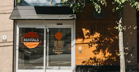 A tree in front of a building with a sign that says rentals.