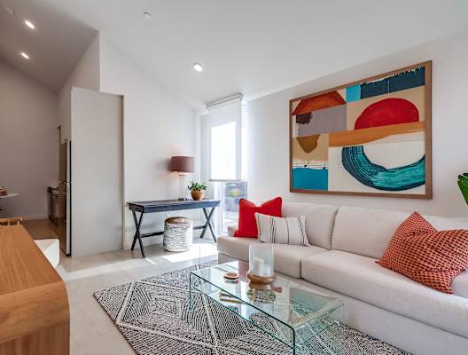 A modern living room with a white sofa and a colorful abstract painting on the wall.