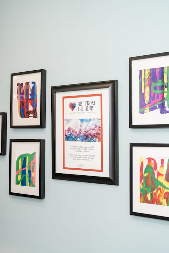 A wall with framed artwork including a piece titled "Art from the Heart".