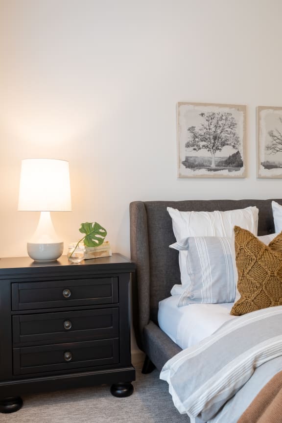 a bedroom with a bed with white pillows and a nightstand with a lamp