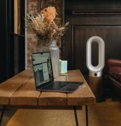 a laptop on a coffee table with a vase of flowers