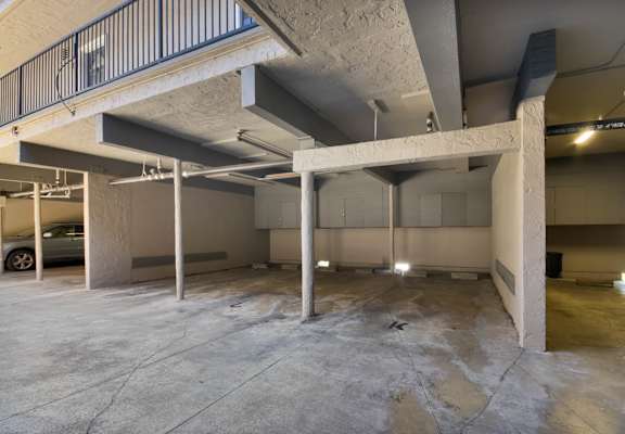 A large, empty parking garage with concrete pillars and a metal railing.