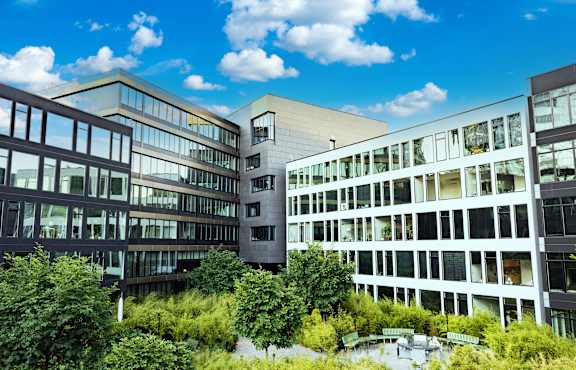 A modern building with a lot of windows and trees in front.