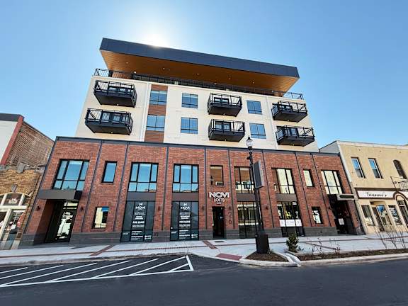 A modern building with a black and white facade and a balcony on the top floor.