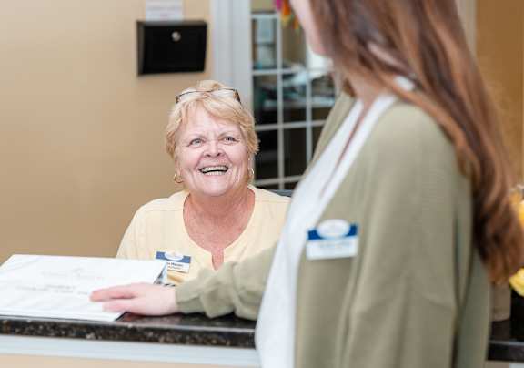 an older woman talking to a nurse in front of a desk