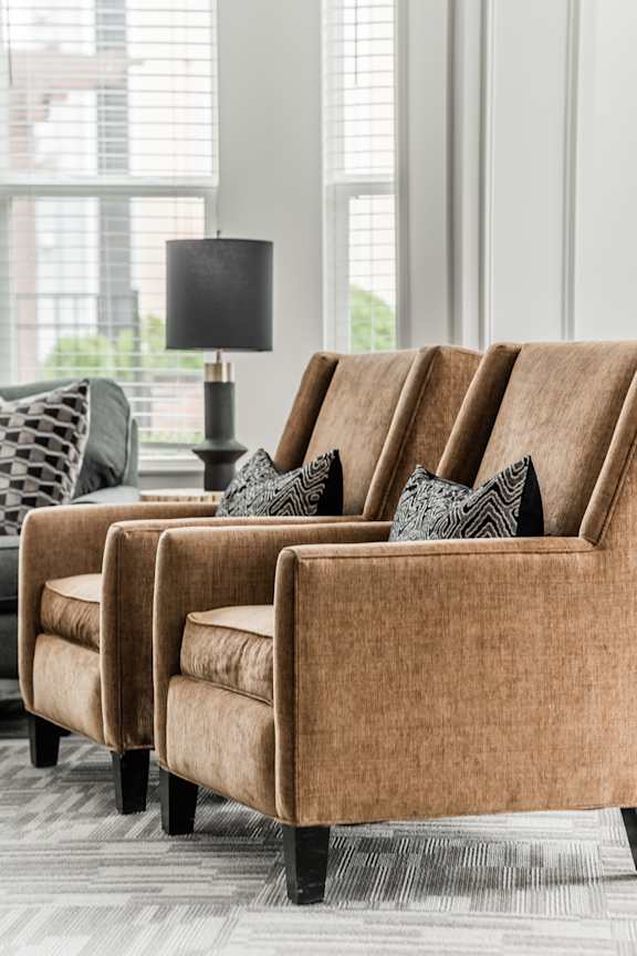 A set of four brown chairs with cushions are arranged in a row.