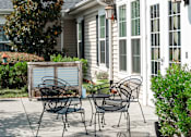 Thumbnail 17 of 17 - A patio with a table and chairs is in front of a house.