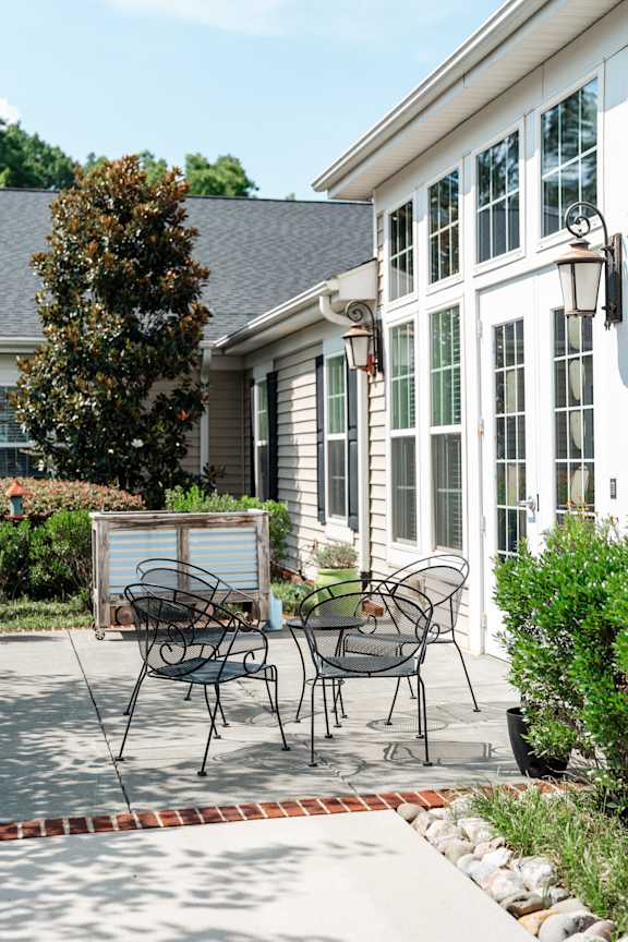 A patio with a table and chairs is in front of a house.